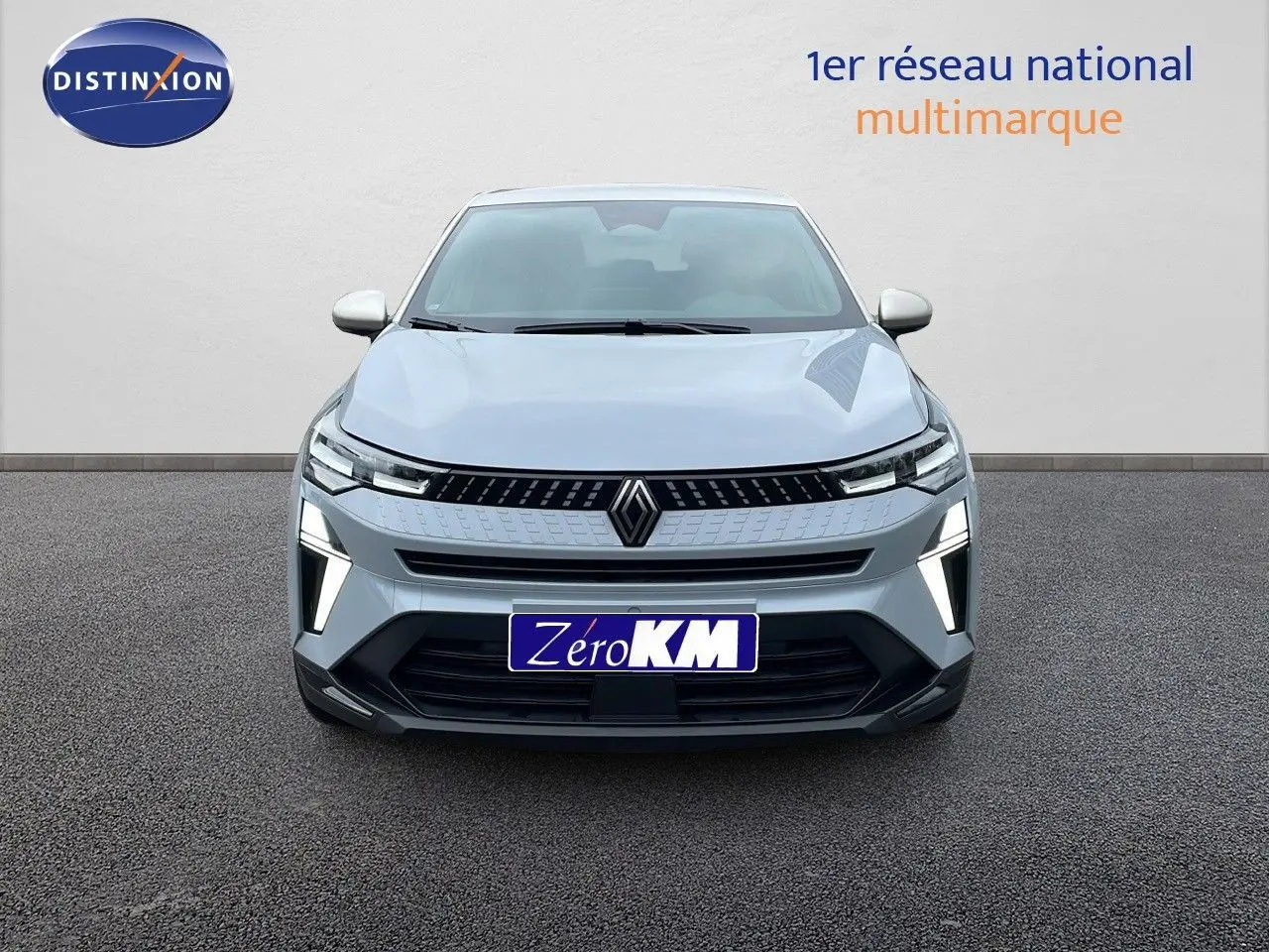 Vue frontale du Renault Captur 1.6 E-TECH hybride 2025 en gris Rafale métal avec éclairage LED distinctif allumé.