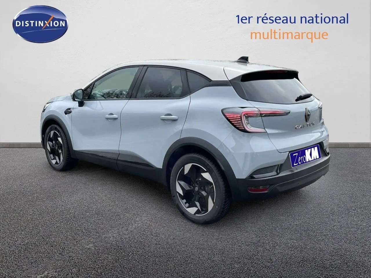 Vue 3/4 arrière droite d'un Renault Captur gris rafale métal avec toit beige, jantes noires et détails noirs contrastants.
