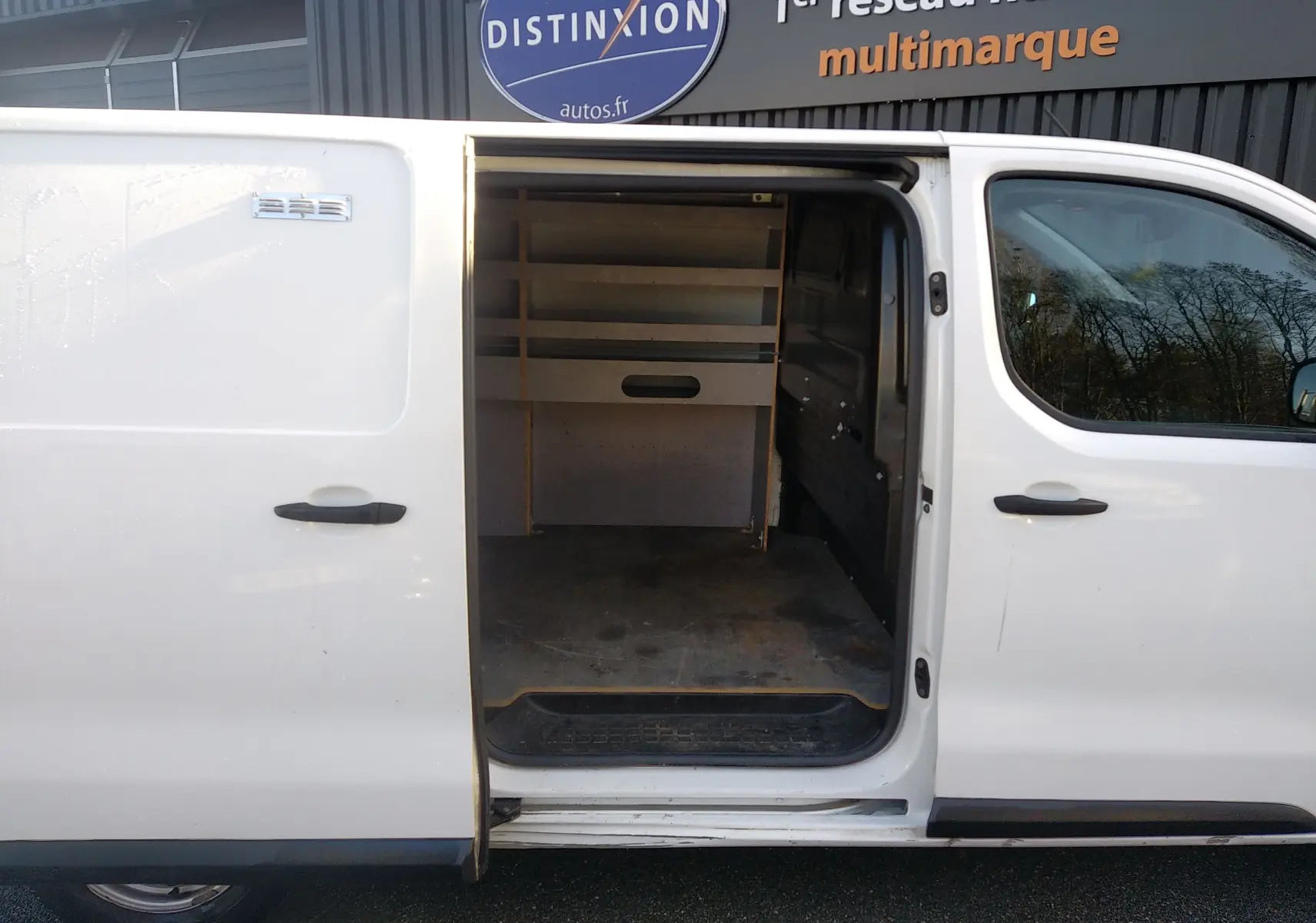 Vue latérale gauche d’un Citroën Jumpy blanc 2021 avec porte coulissante ouverte montrant l’espace de chargement aménagé.