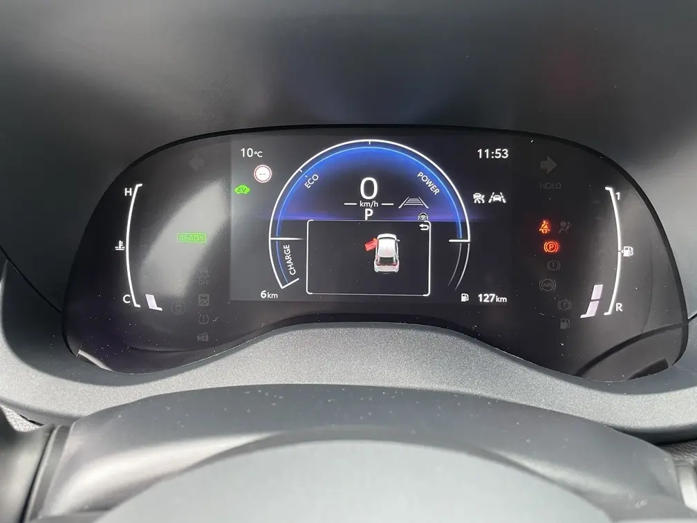 Tableau de bord numérique de la Toyota Yaris Cross 2026 affichant la vitesse, l'autonomie et les alertes en vue frontale.