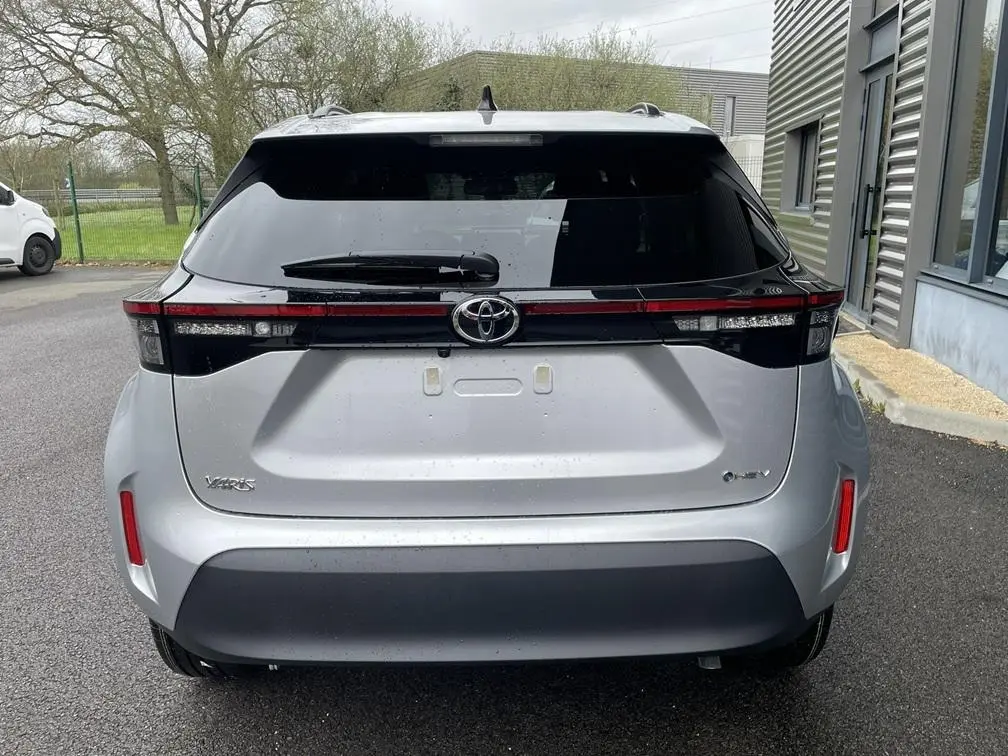 Vue arrière d'une Toyota Yaris Cross gris clair avec feux arrière reliés par une bande noire brillante.