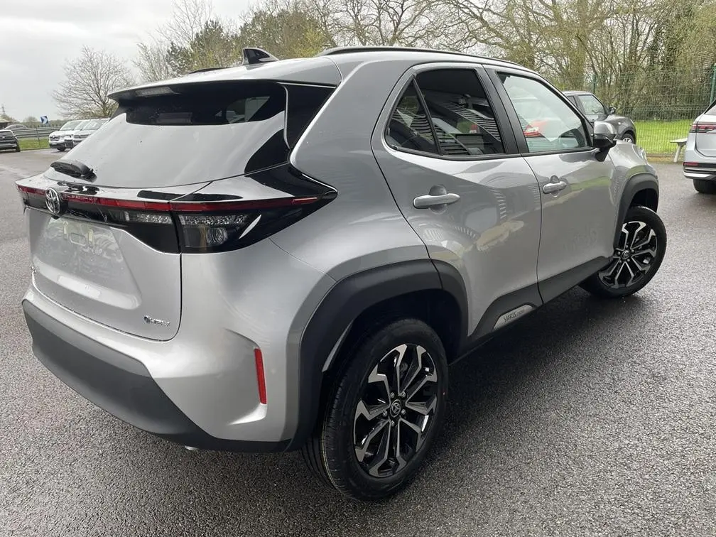 Vue 3/4 arrière droite d'une Toyota Yaris Cross gris clair avec toit noir et jantes alliage noires.