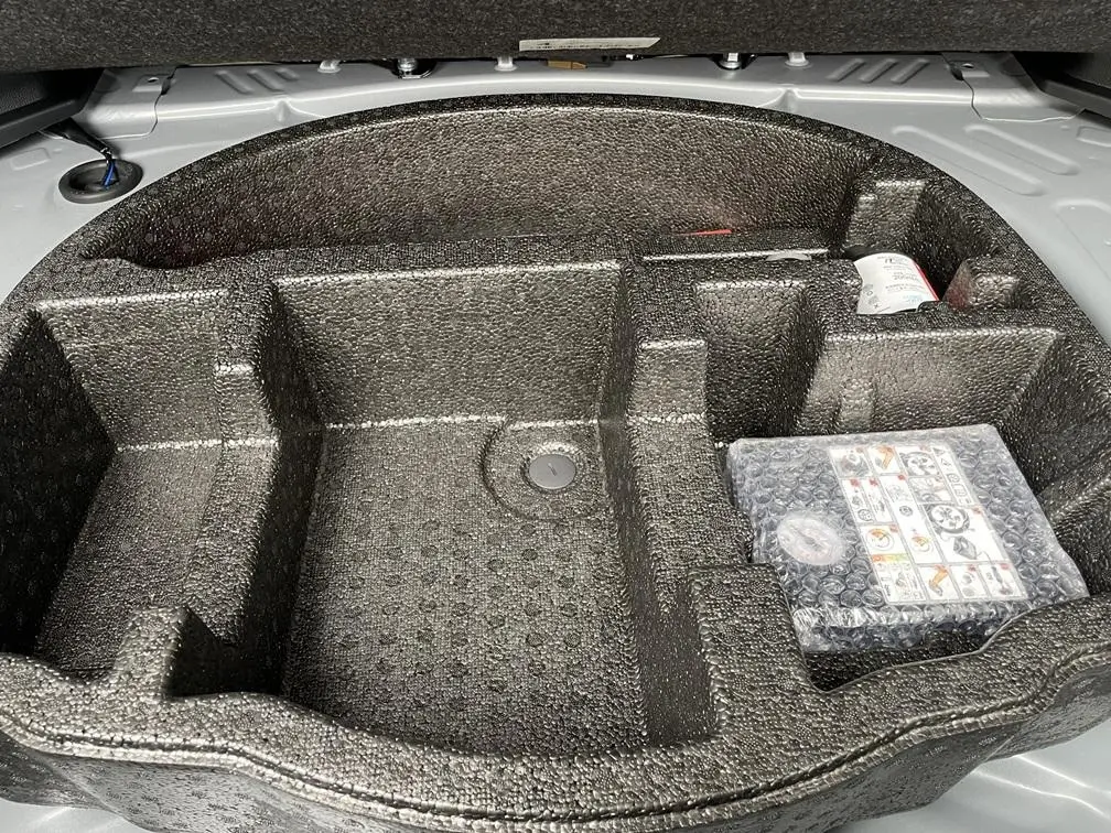 Vue rapprochée du rangement en mousse noire dans le coffre gris clair de la Toyota Yaris Cross 2026.