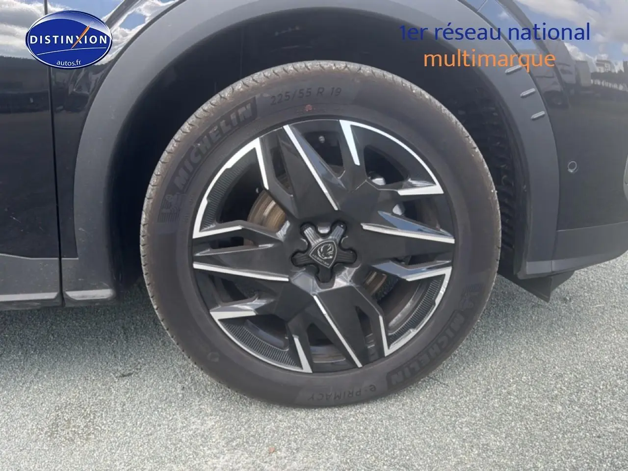 Gros plan sur la roue avant gauche noire d’un Peugeot 5008 Hybrid 145 allure e-dcs6 avec jante alu stylisée.