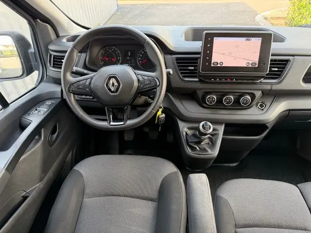 Vue intérieure avant du Renault Trafic Combi 2022 avec tableau de bord noir, volant multifonction et écran tactile central.