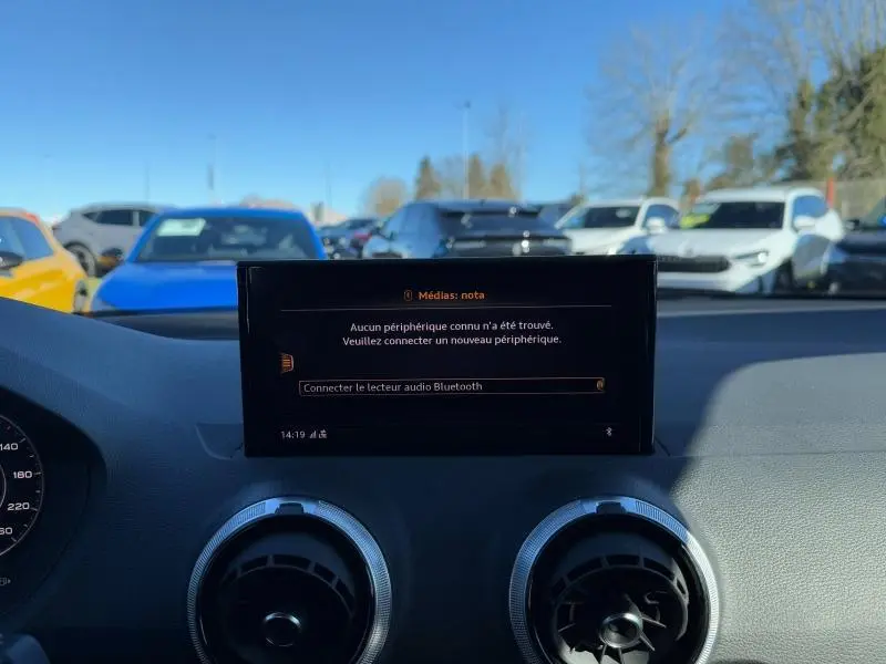 Vue intérieure du tableau de bord de l'Audi Q2 2024, écran central affichant la connexion Bluetooth, volant partiellement visible.