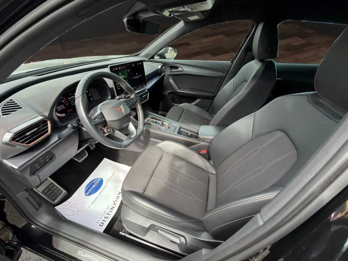Vue intérieure côté conducteur de la CUPRA Formentor noire avec volant cuir, écran tactile central et sièges sport noirs.