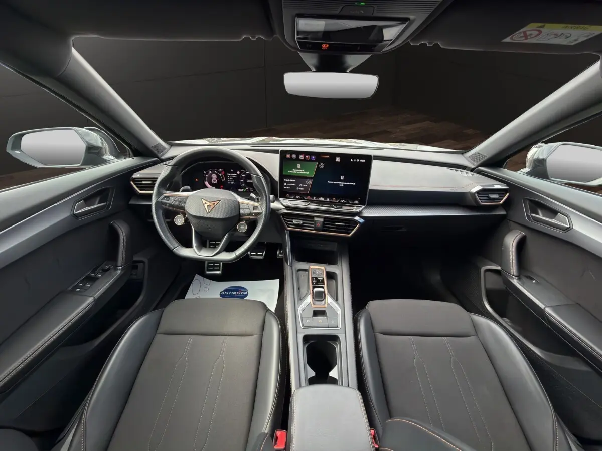 Vue intérieure avant du CUPRA Formentor 2025 avec tableau de bord noir, écran tactile central et volant cuir alu.