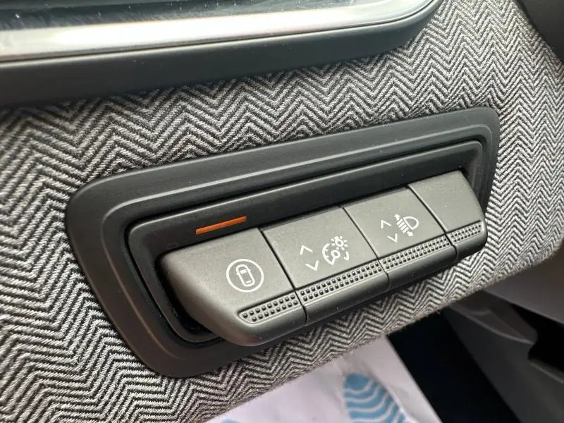 Gros plan sur les boutons de réglage d’éclairage et verrouillage sur la garniture grise à chevrons de la Renault Clio Rouge Flamme 2025.