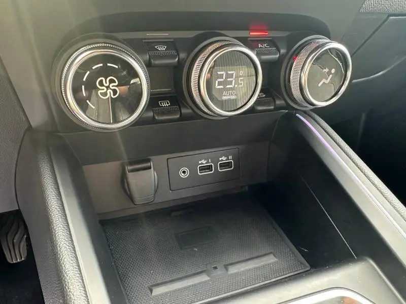 Vue rapprochée de la console centrale noire de la Renault Clio 1.0 Eco-G 2025, avec commandes climatisation et ports USB.