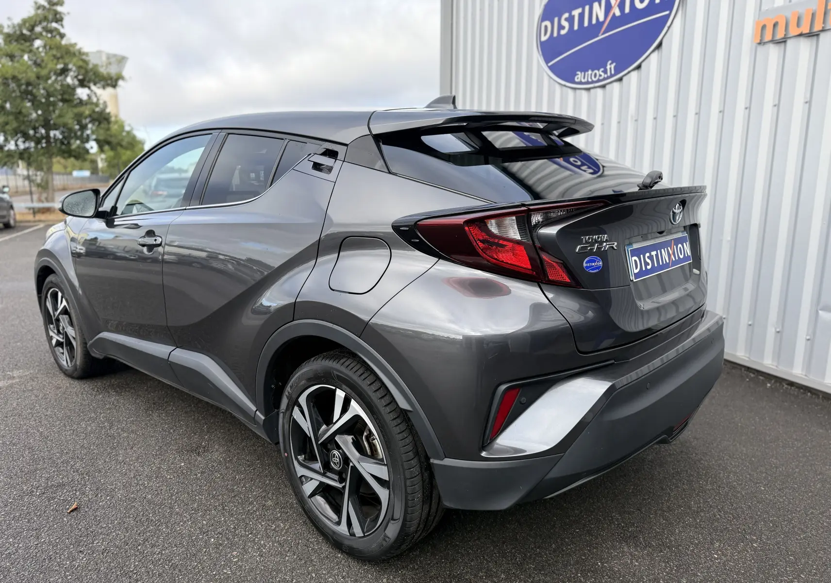 Vue 3/4 arrière droite du Toyota C-HR 1.8 hybrid gris atlas, soulignant ses lignes dynamiques et ses jantes bi-ton.