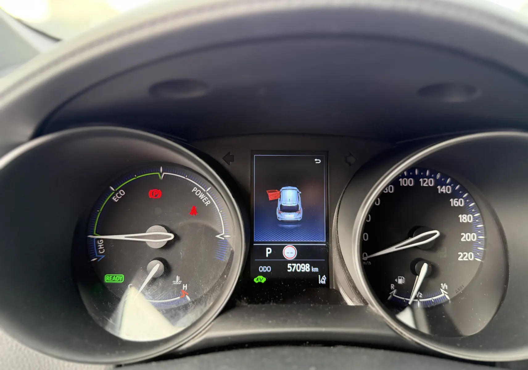 Tableau de bord du Toyota C-HR hybride gris atlas 2023, affichage digital central avec porte avant gauche ouverte.