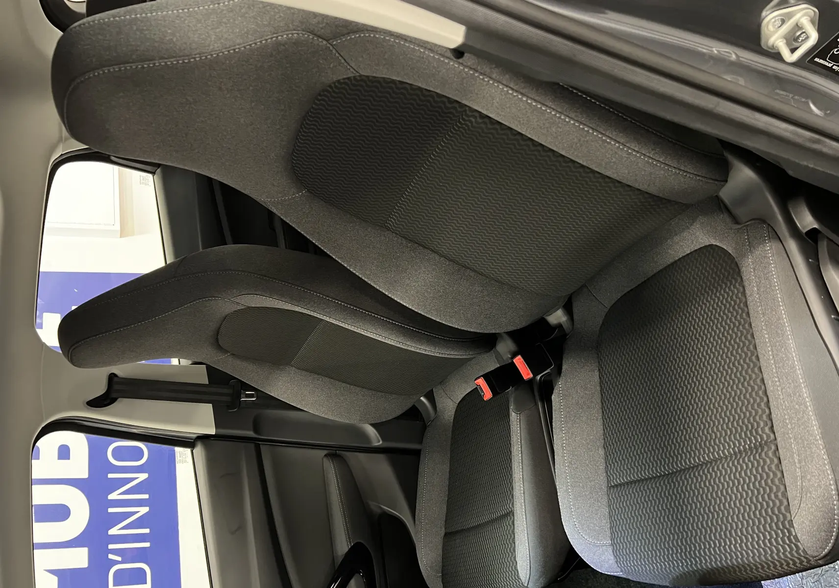 Vue rapprochée des sièges avant en tissu gris foncé de la Dacia Spring LEAP MOTOR T03 blanche, intérieur sobre et moderne.