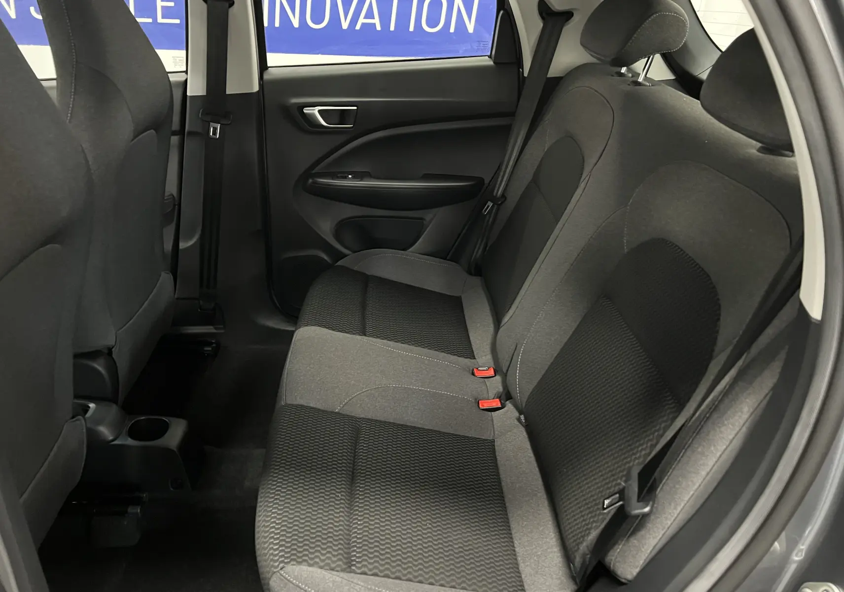 Vue intérieure côté droit des sièges arrière en tissu gris et noir du Dacia Spring blanc électrique.