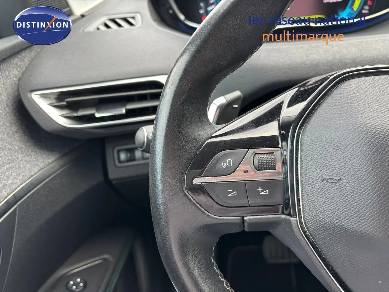 Gros plan sur le volant multifonction noir du Peugeot 3008 1.6 Hybrid 225, avec commandes audio et régulateur.