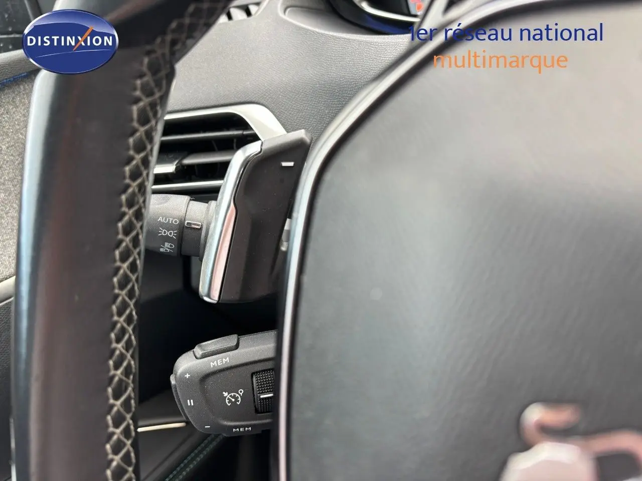 Gros plan sur la commande de régulateur de vitesse derrière le volant d’un Peugeot 3008 bleu Celebes hybride rechargeable.