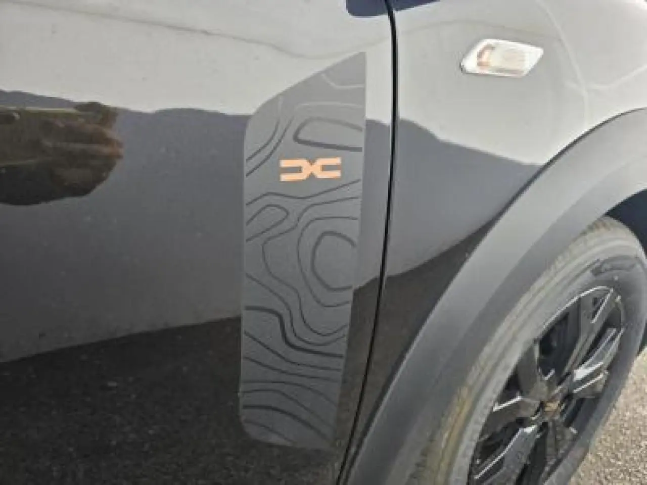 Détail du sticker topographique noir et orange sur la porte côté gauche d'une Dacia Sandero Stepway noir nacré.