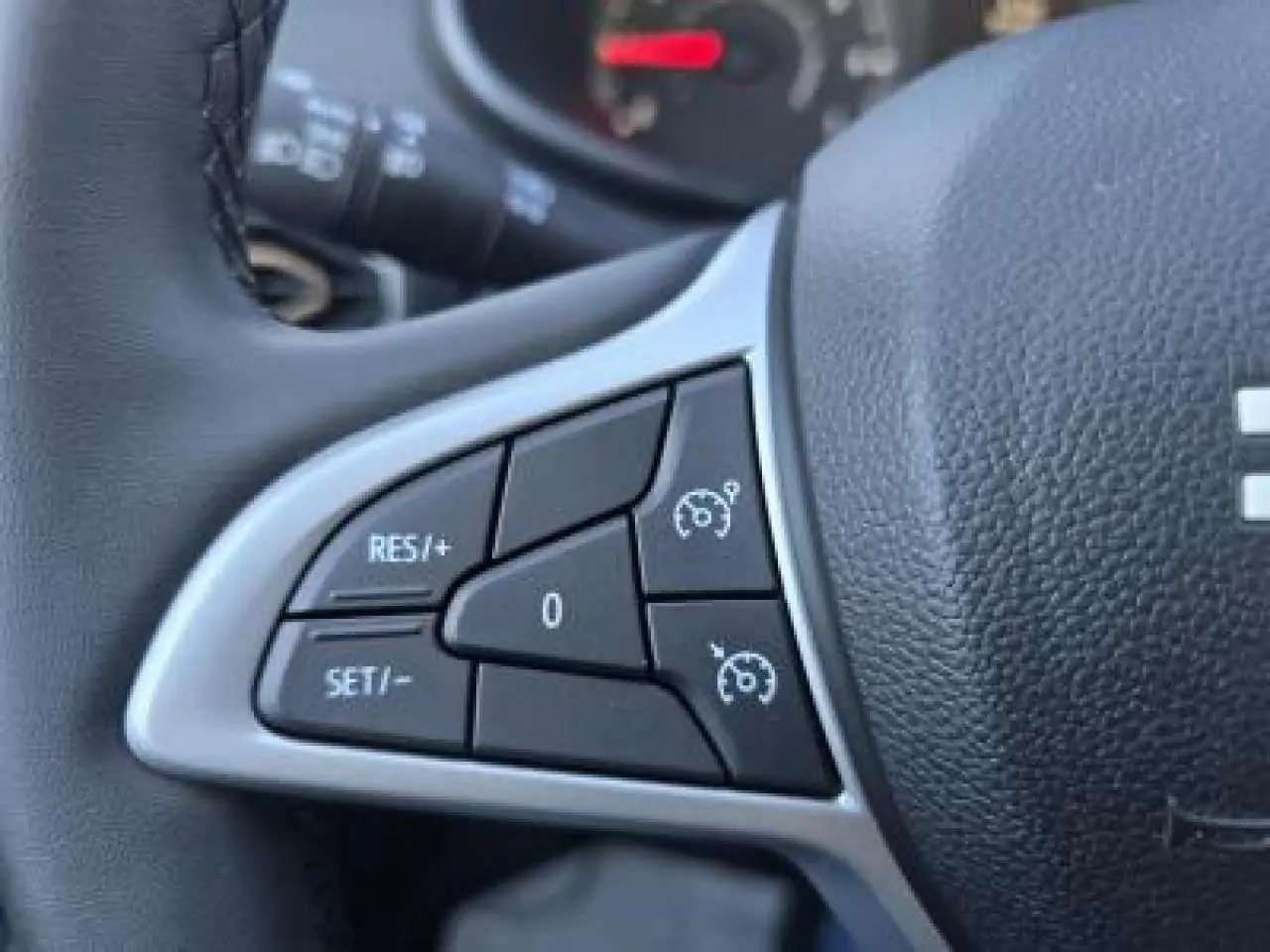 Gros plan sur les commandes du régulateur de vitesse au volant cuir noir du Dacia Sandero Stepway 2025.