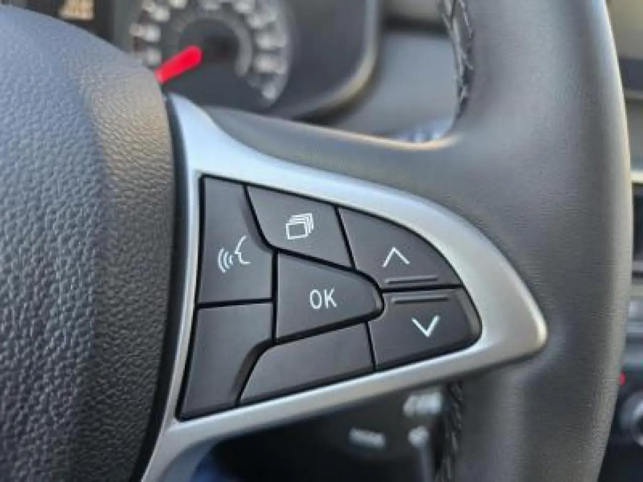 Gros plan sur les commandes multifonctions à gauche du volant noir du Dacia Sandero Stepway 2025.