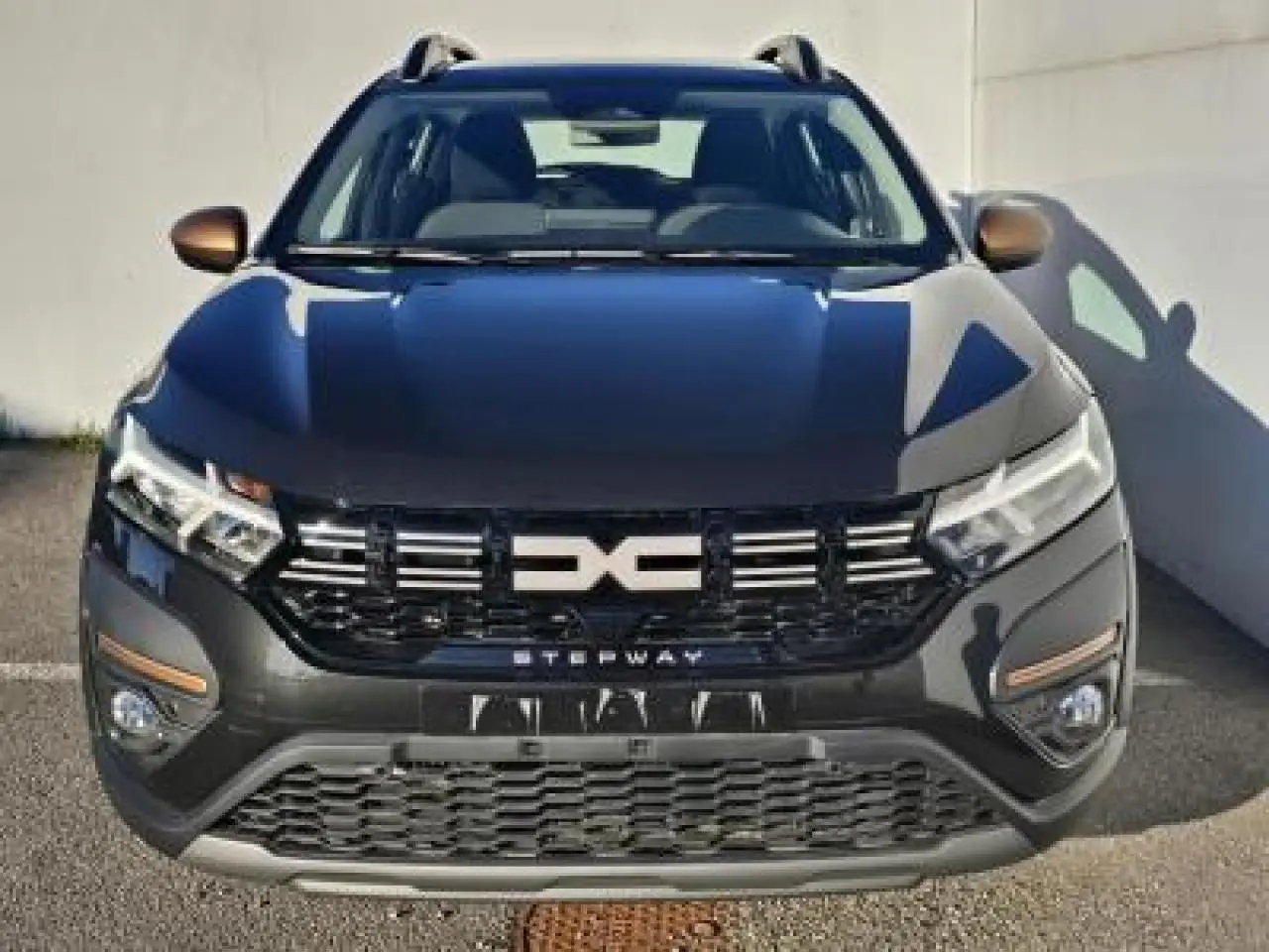 Vue avant d'une Dacia Sandero III Stepway 2025 noir nacré avec calandre marquée Stepway et barres de toit visibles.