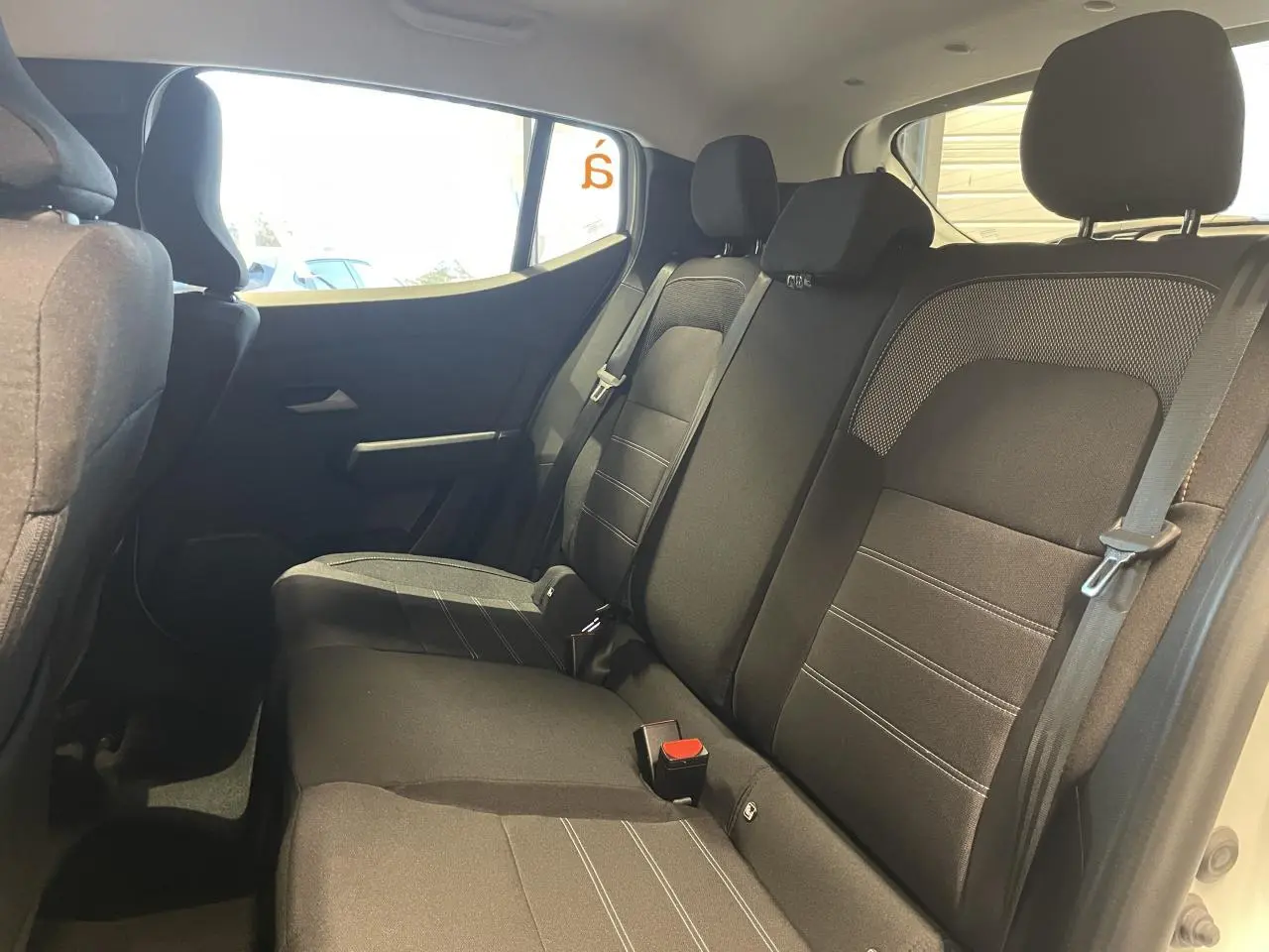 Vue intérieure côté droit sur la banquette arrière noire du Dacia Sandero Stepway 2025 avec appuie-têtes et ceintures visibles.