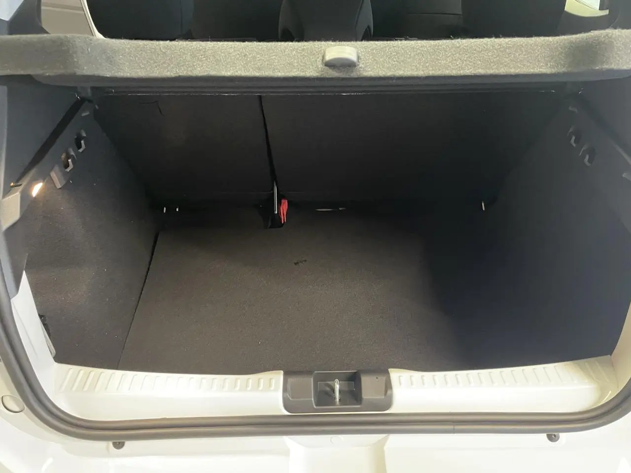 Coffre ouvert vu de l'arrière d'une Dacia Sandero Stepway blanc glacier, avec banquette arrière rabattable.