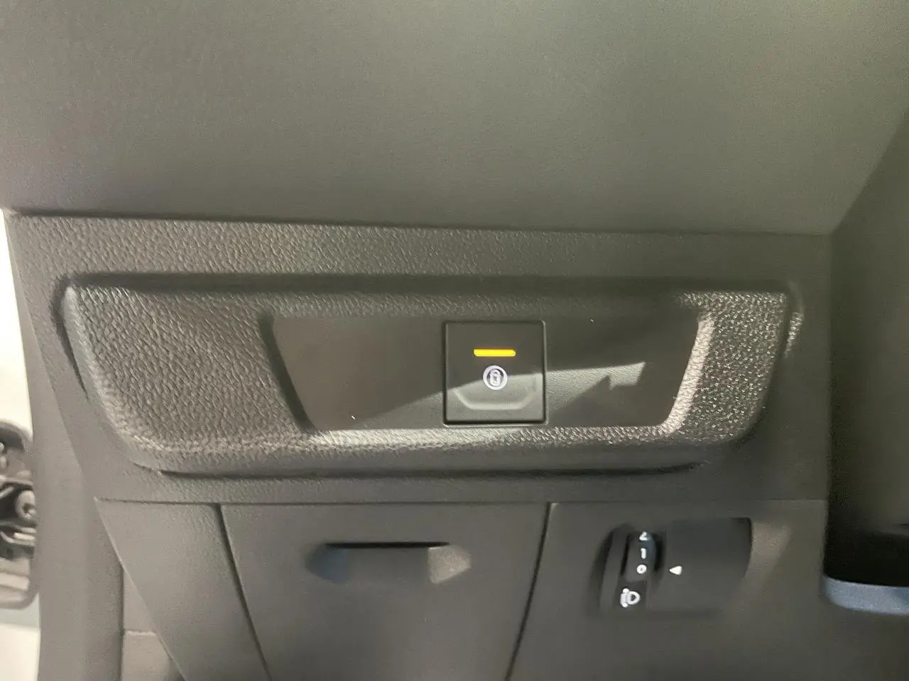 Gros plan sur le bouton de frein de stationnement électrique dans l’habitacle d’une Dacia Sandero Blanc Glacier 2025.