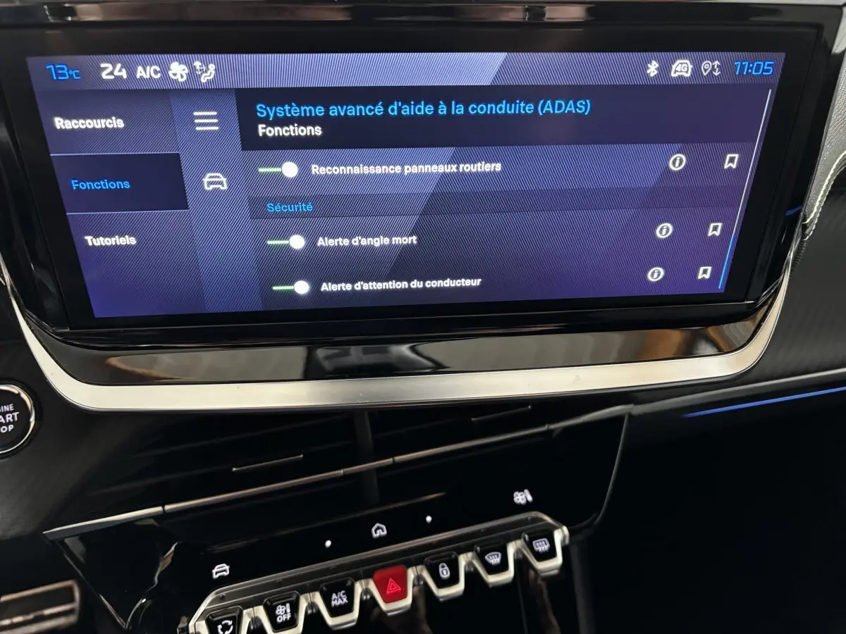 Écran tactile central affichant les aides à la conduite du Peugeot 208 Hybrid 110 e-DCS6 GT, intérieur noir.