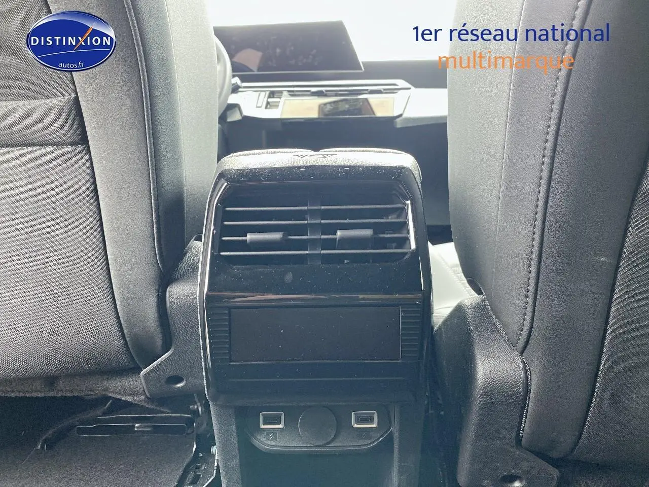 Vue intérieure centrée sur la console arrière noire entre les sièges avant gris du Peugeot 5008 Hybrid 145 allure 2025.