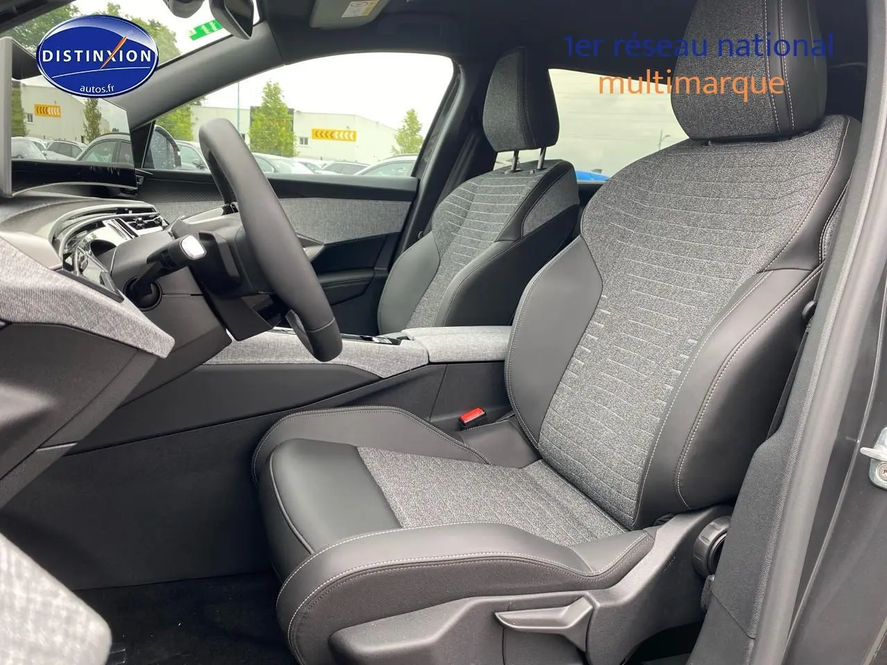 Vue intérieure côté conducteur du Peugeot 5008 Hybrid 145 allure e-dcs6 2025, sièges tissu gris et cuir noir.