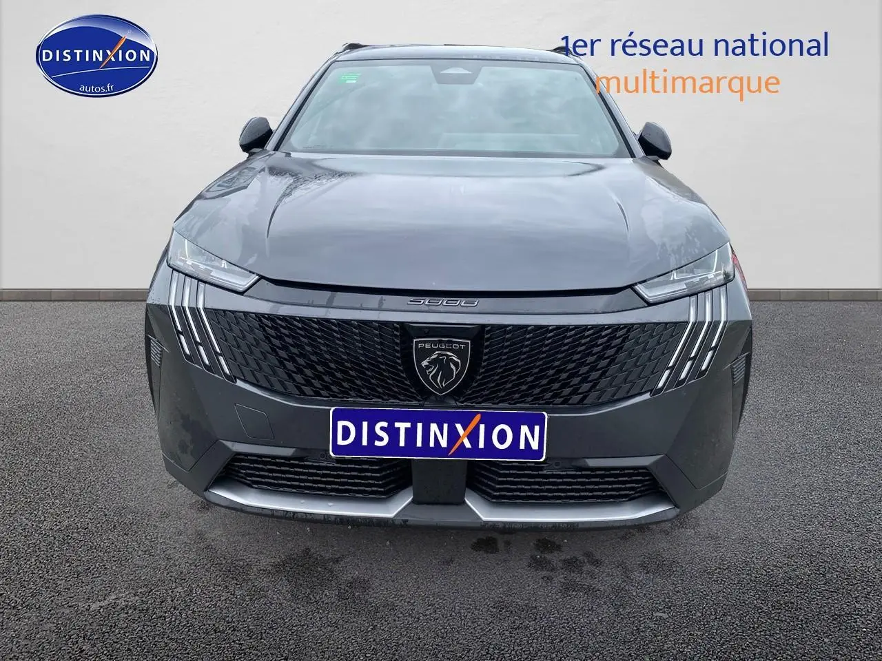 Vue avant du Peugeot 5008 Hybrid gris titane avec calandre noire et feux LED distinctifs en griffes.