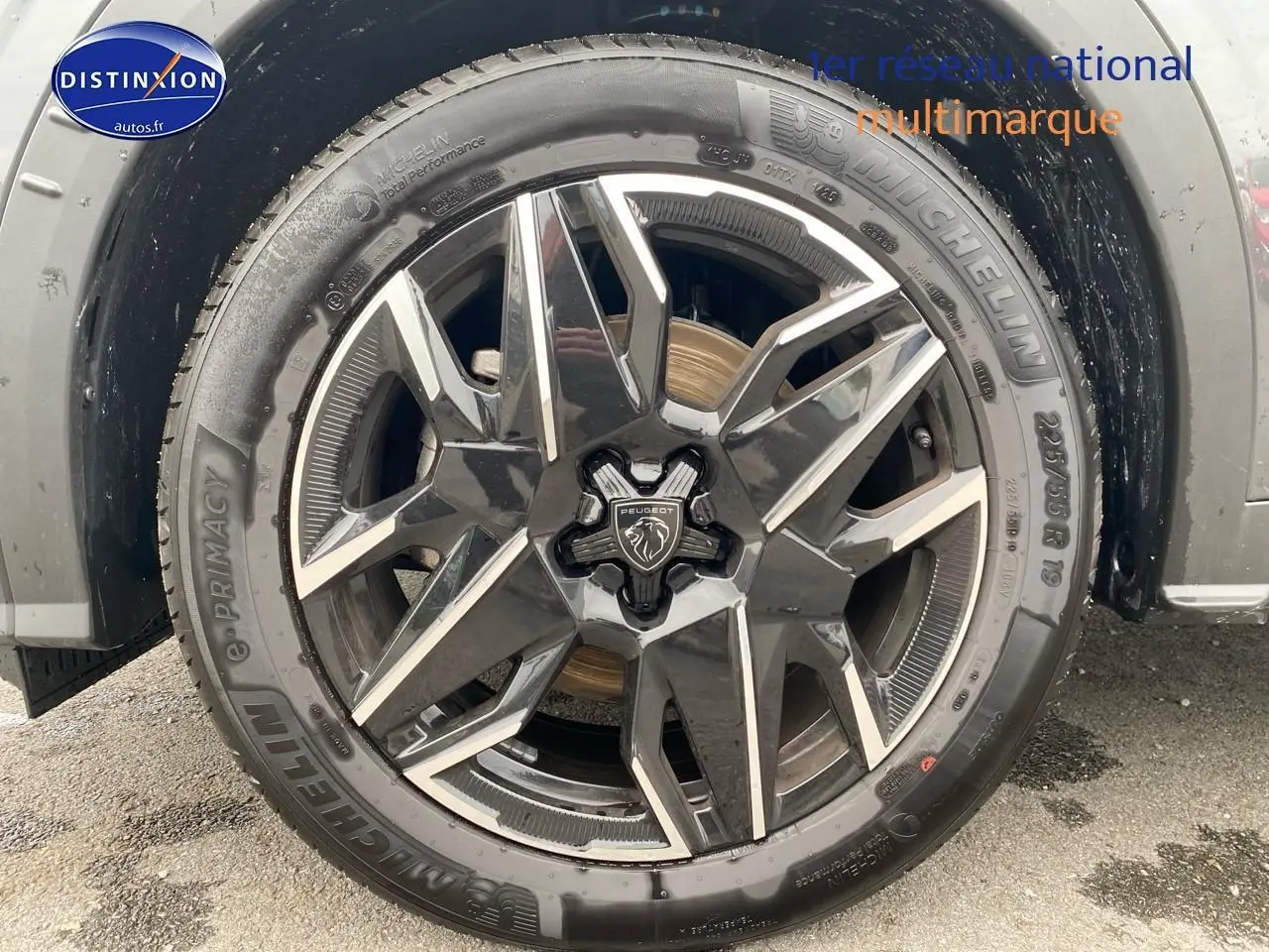 Gros plan sur la jante alu noire et argentée d’un Peugeot 5008 gris titane, mettant en valeur le logo central lion.