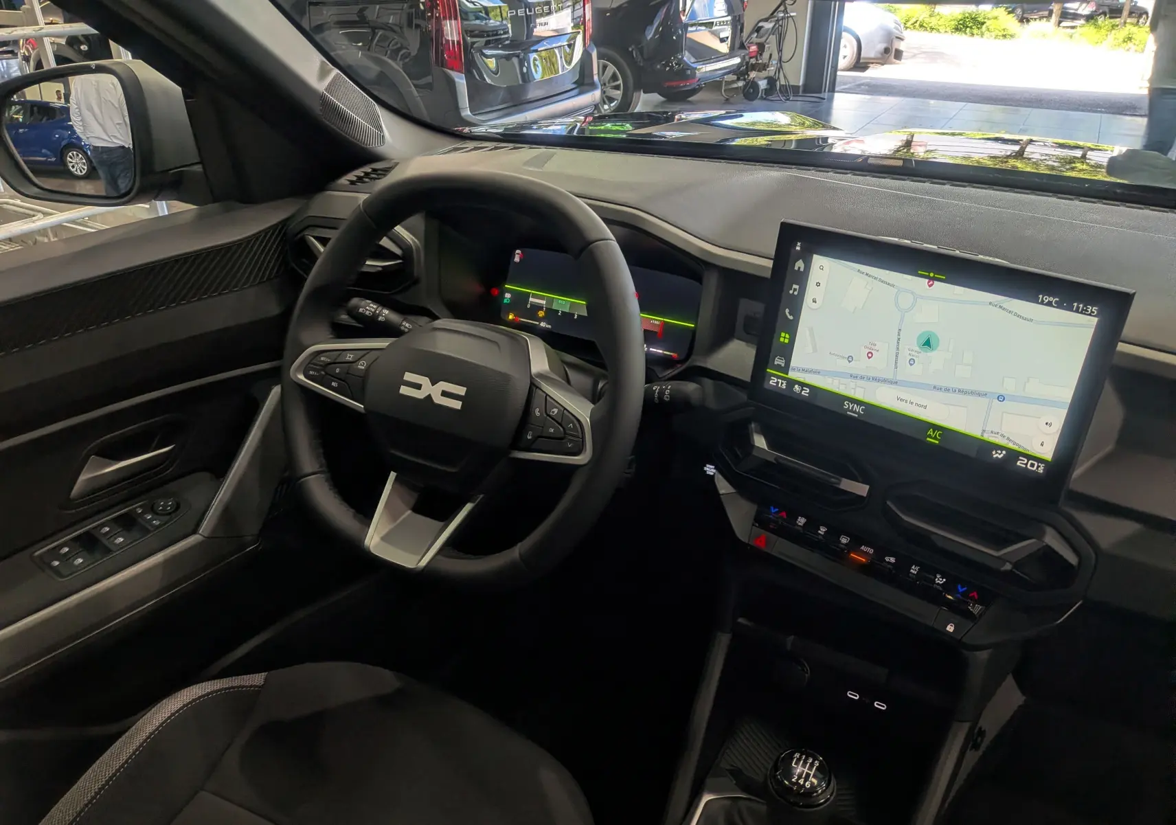Vue intérieure côté conducteur du Dacia Bigster bleu indigo 2026, avec tableau de bord numérique et écran tactile central.