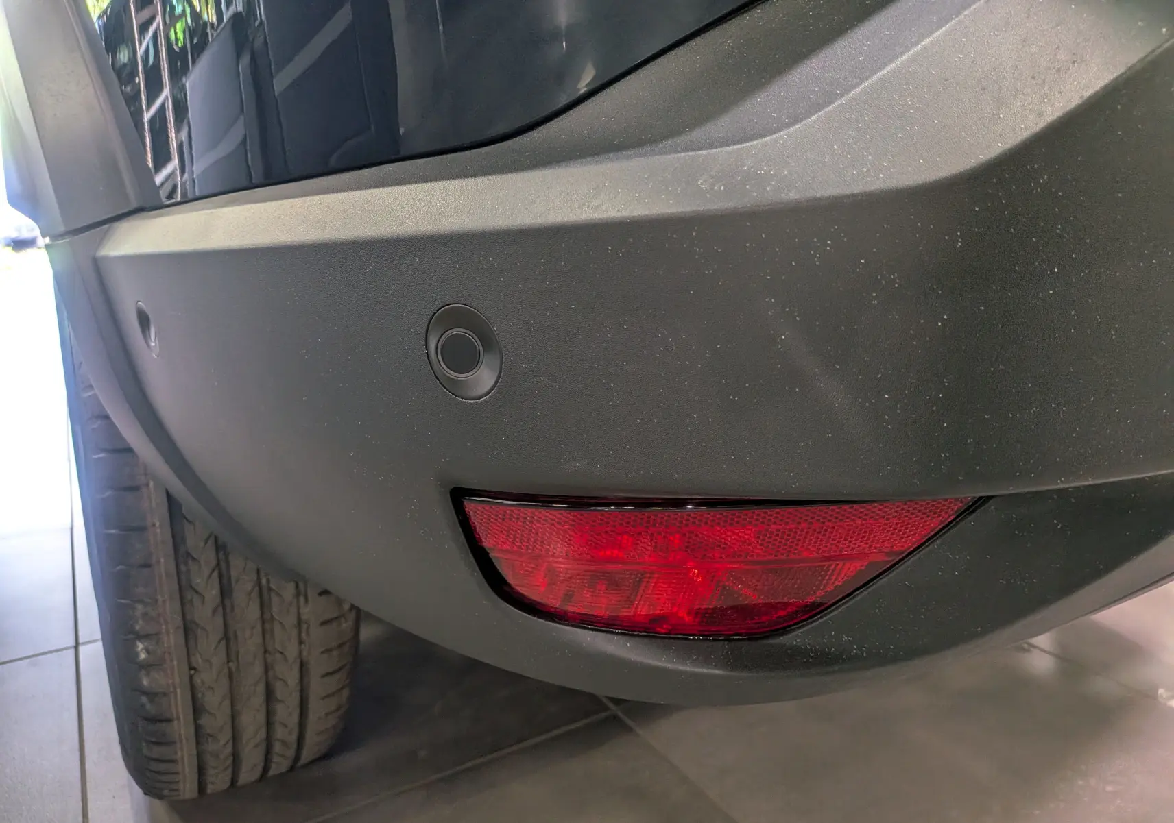 Gros plan sur le pare-chocs arrière droit bleu indigo du Dacia Bigster 2026 avec feu rouge et capteurs de recul.