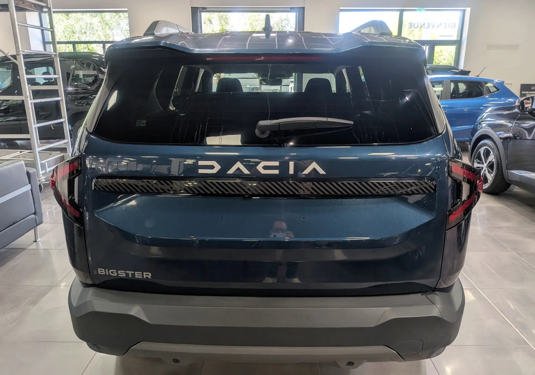 Vue arrière du Dacia Bigster bleu indigo avec logo DACIA lumineux et feux arrière en forme de C.