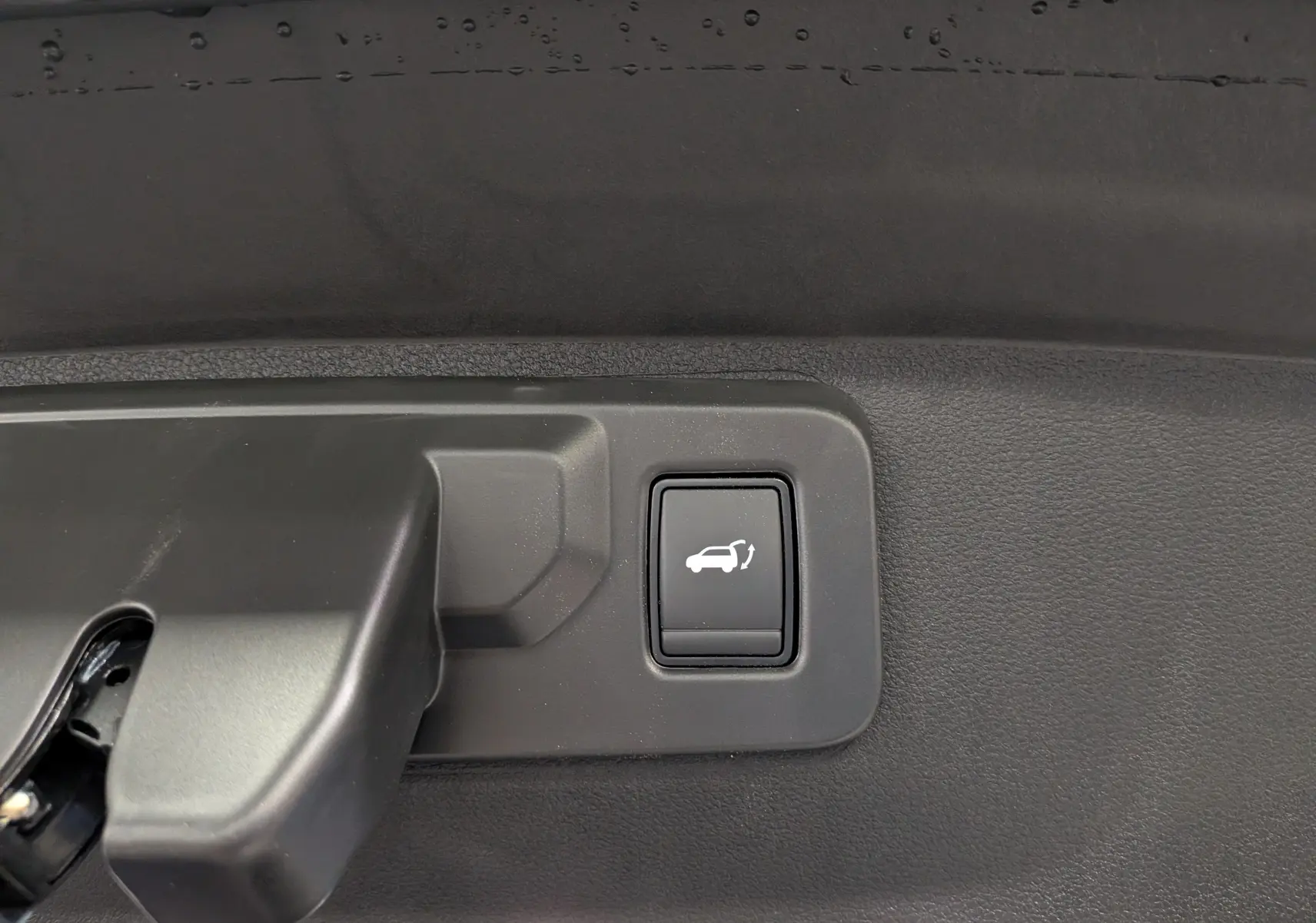 Bouton d'ouverture électrique du hayon sur la garniture intérieure d'un Renault Rafale gris Schiste.