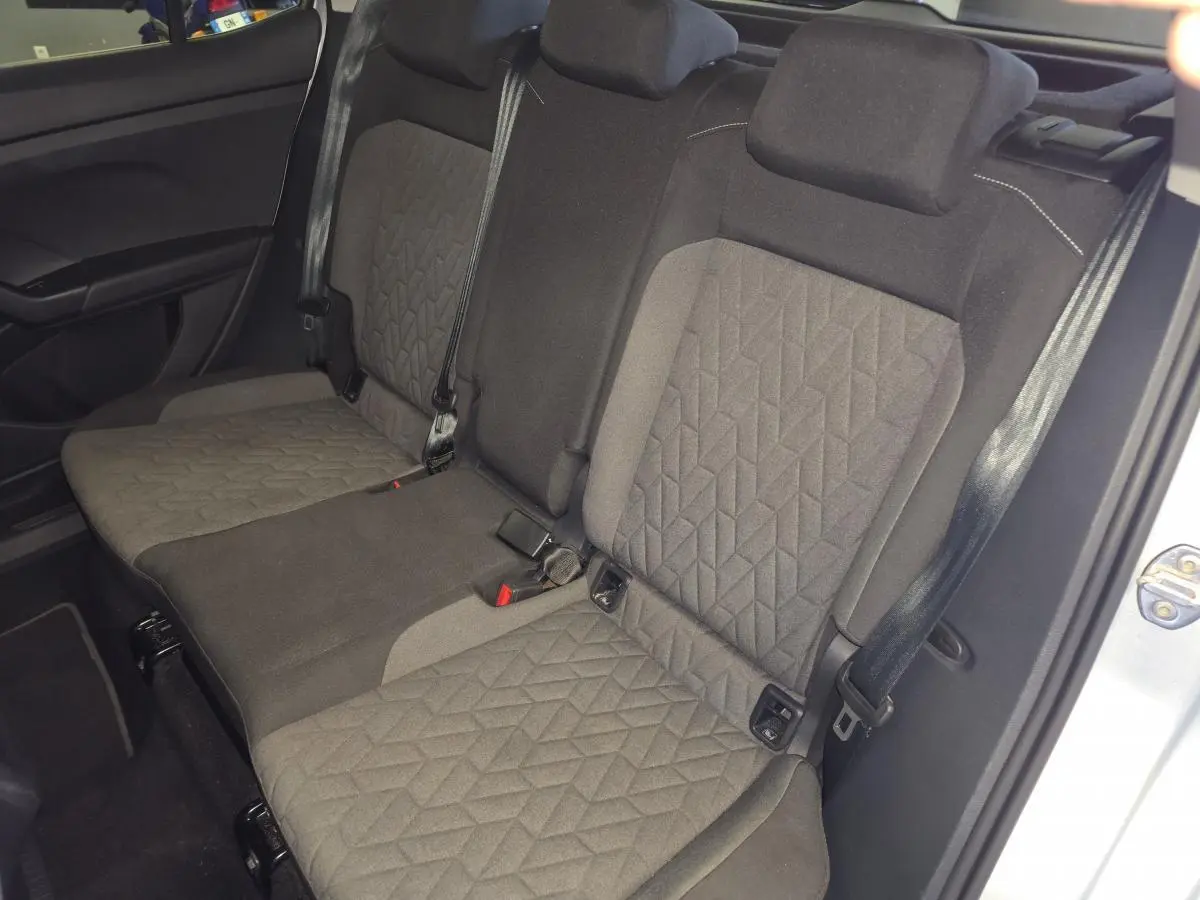 Vue intérieure de la banquette arrière en tissu gris du Volkswagen T-Cross 2025, avec ceintures de sécurité visibles.