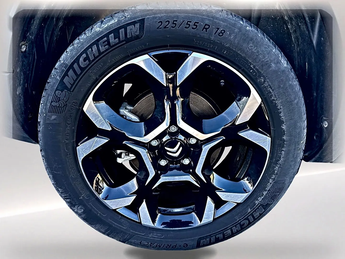 Gros plan sur la jante alu noire et chromée avec logo Citroën d’un pneu Michelin d’un Citroën C5 Aircross noir.