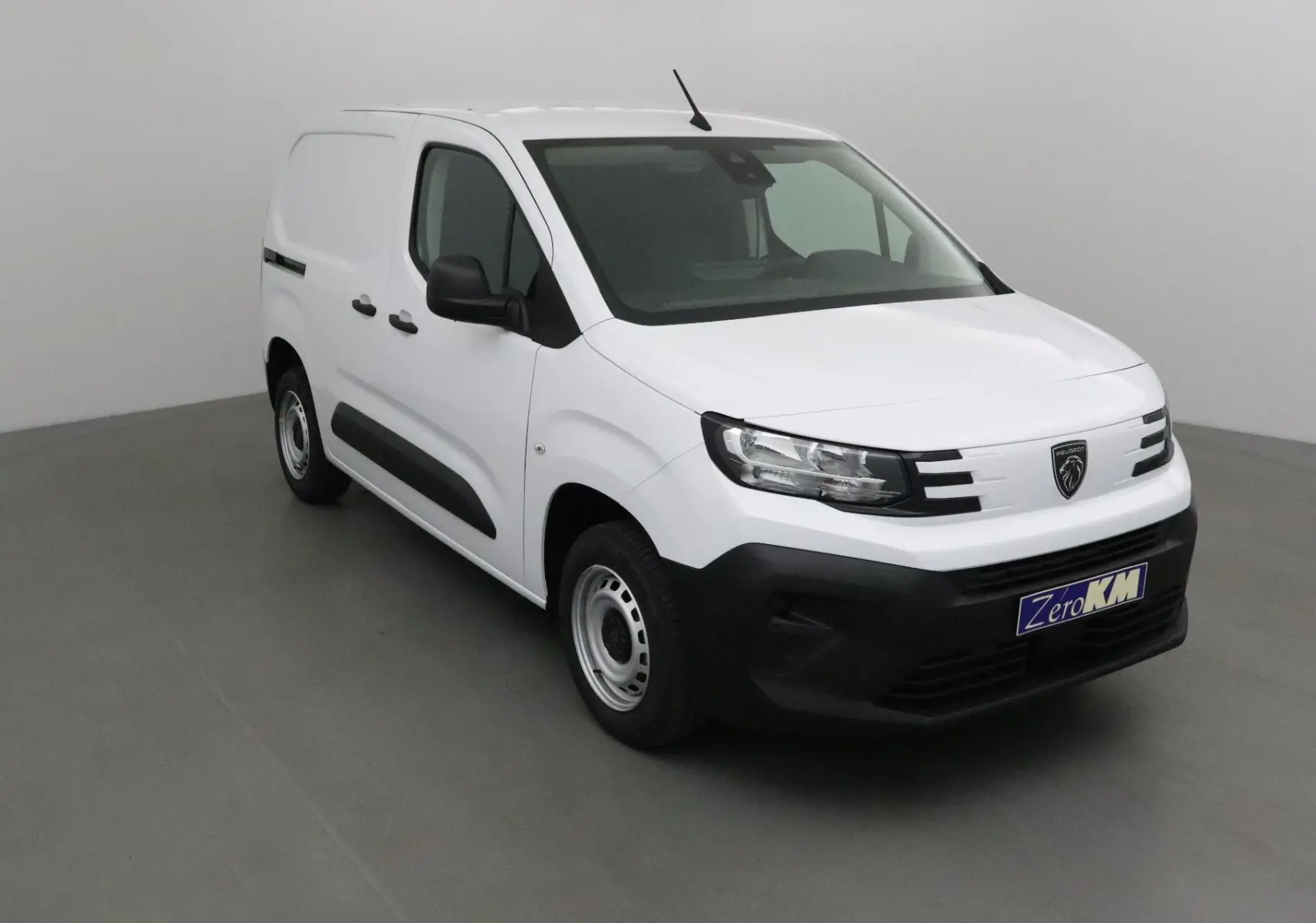 Peugeot Partner blanc en vue 3/4 avant droit, avec pare-chocs noir et jantes acier simples.