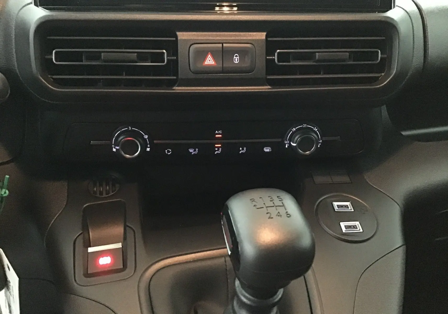 Vue rapprochée de la console centrale du Peugeot Partner 2025, montrant la boîte manuelle et les commandes de climatisation.