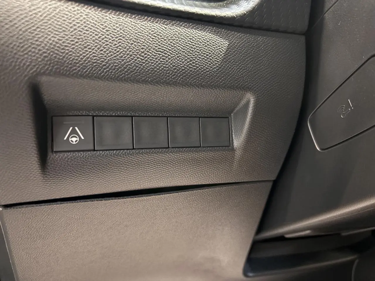 Gros plan sur les boutons de commande du système d’aide à la conduite dans l’habitacle noir du Peugeot 2008 hybride.
