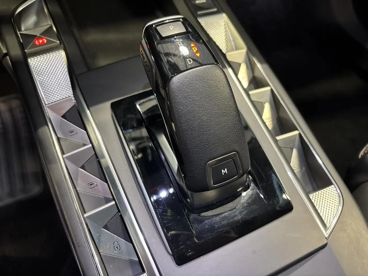 Gros plan sur la commande de boîte automatique noire du DS3 Crossback 2024, avec boutons de contrôle et finitions argentées.