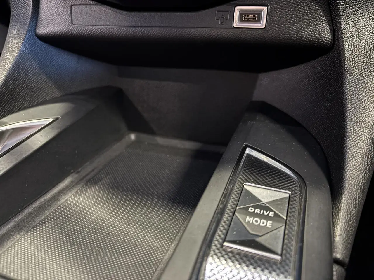 Gros plan sur la console centrale du DS3 Crossback 2024, bouton Drive Mode et port USB-C visibles, intérieur noir.