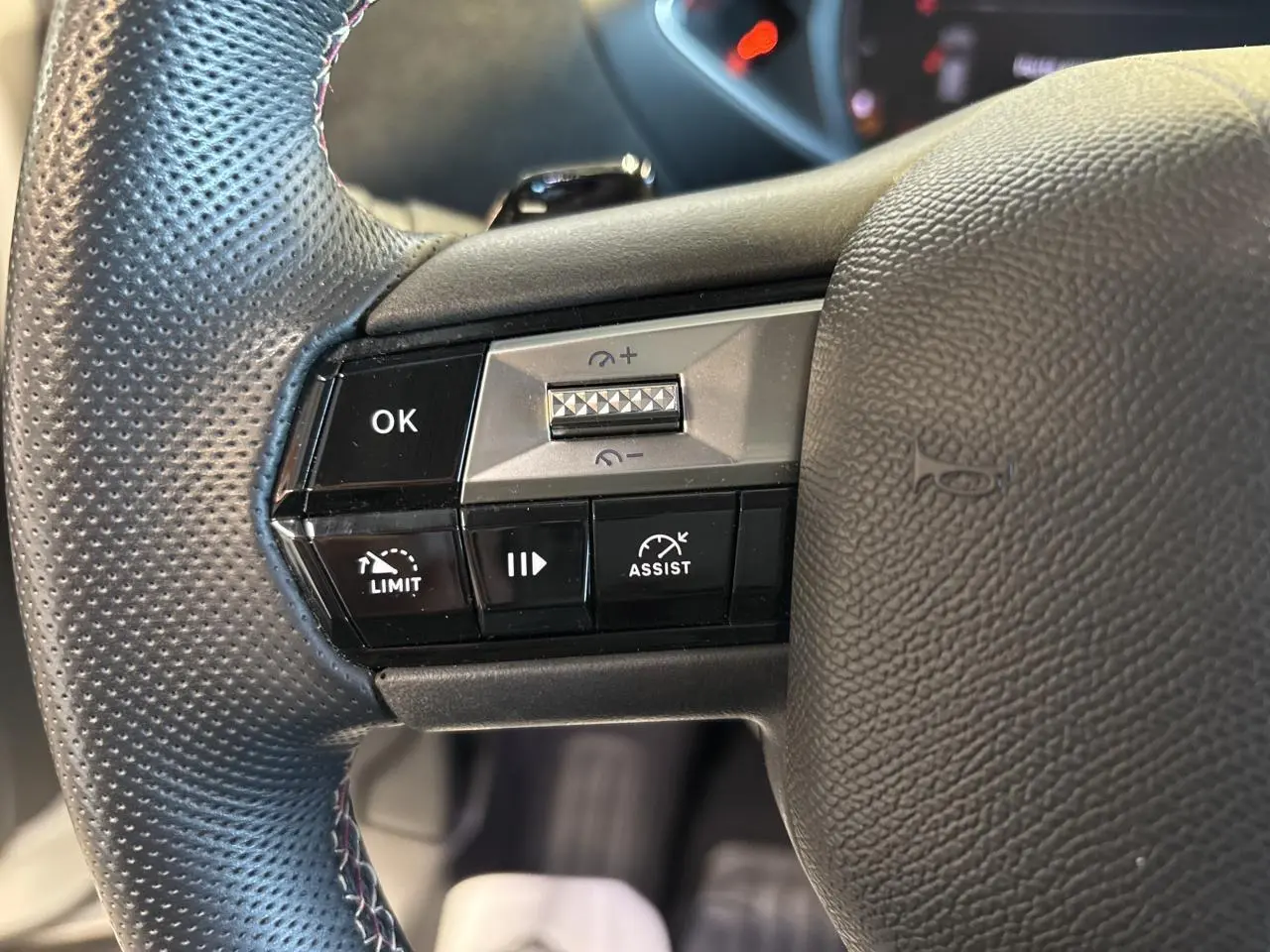 Gros plan sur les commandes au volant côté gauche du DS3 Crossback 2024 en cuir perforé noir.