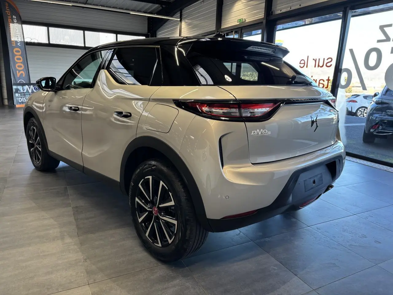 Vue 3/4 arrière droite du DS3 Crossback 2024 en couleur Crystal Pearl avec toit noir et jantes noires en concession.