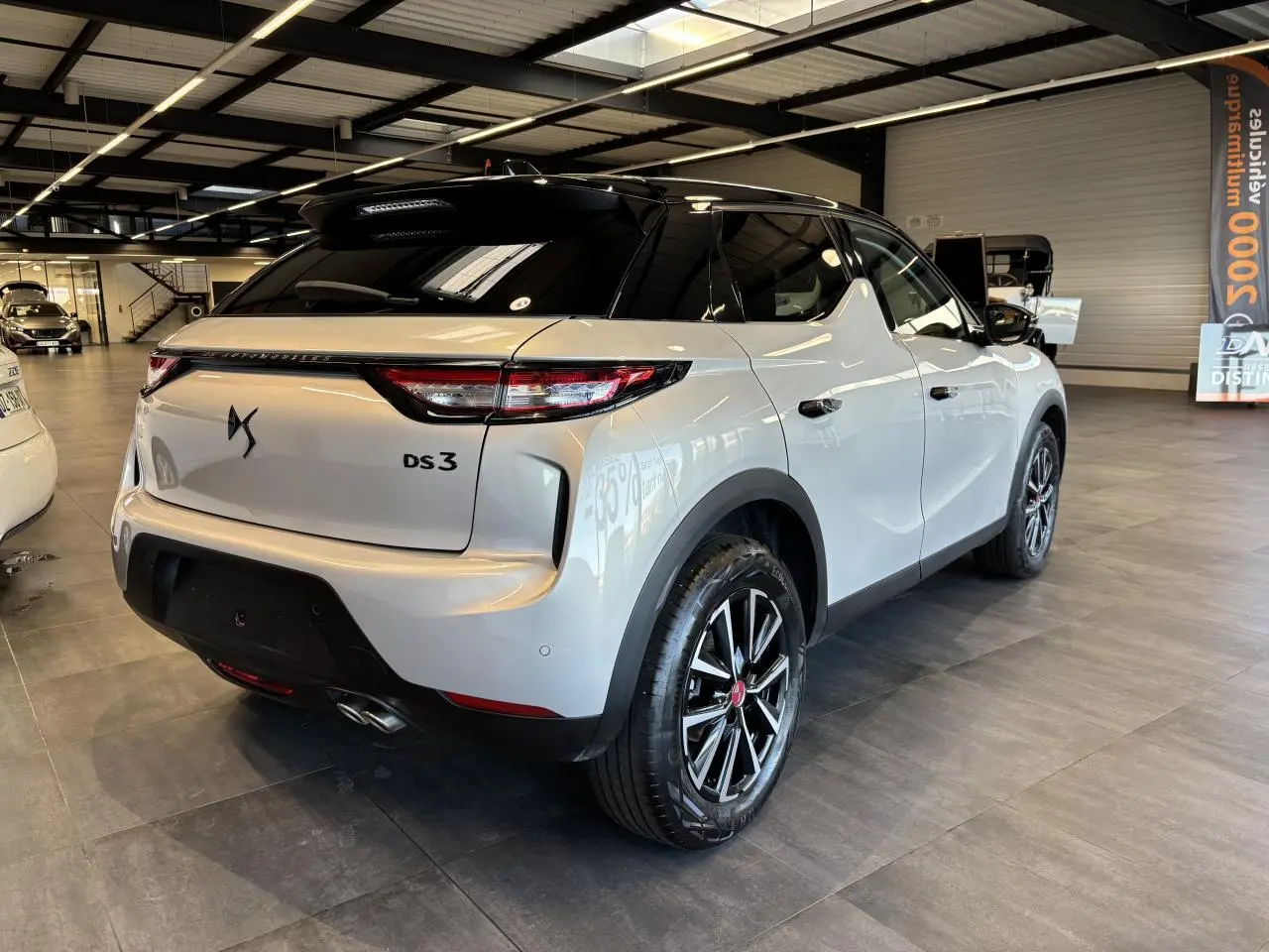 Vue 3/4 arrière droite du DS3 Crossback 2024 en blanc Crystal Pearl avec toit noir et jantes alliage noires.