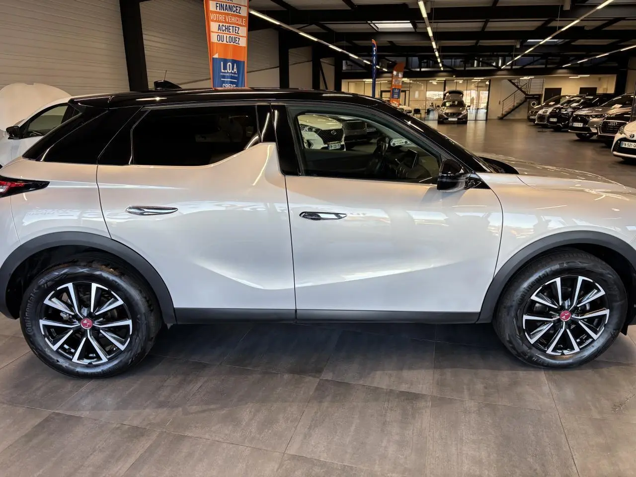 Vue de profil côté gauche du DS3 Crossback 2024 en Crystal Pearl, avec toit noir et jantes noires à détails argentés.