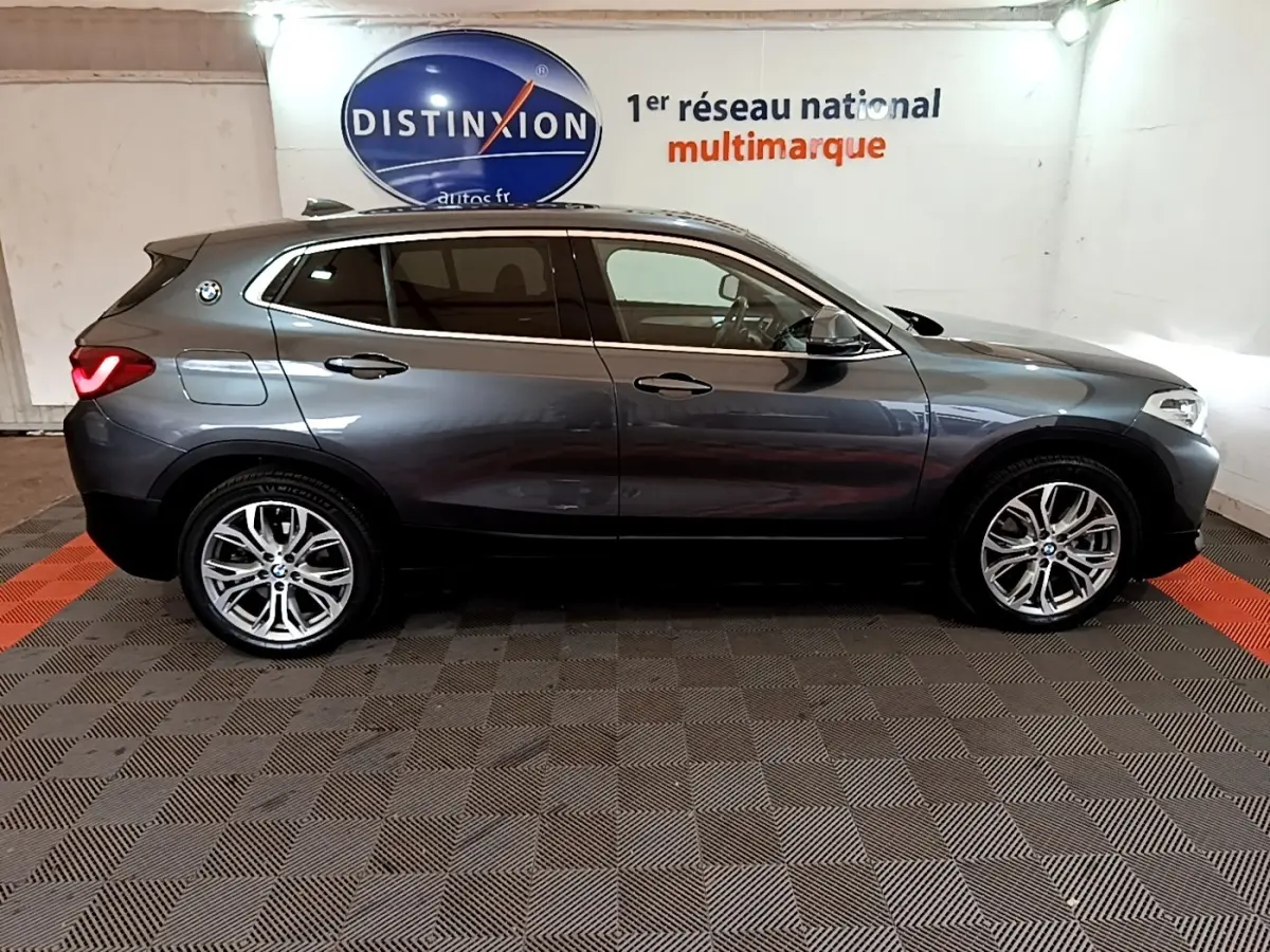 Vue de profil côté gauche d’un BMW X2 xDrive25e hybride rechargeable gris foncé avec jantes alliage et toit noir.