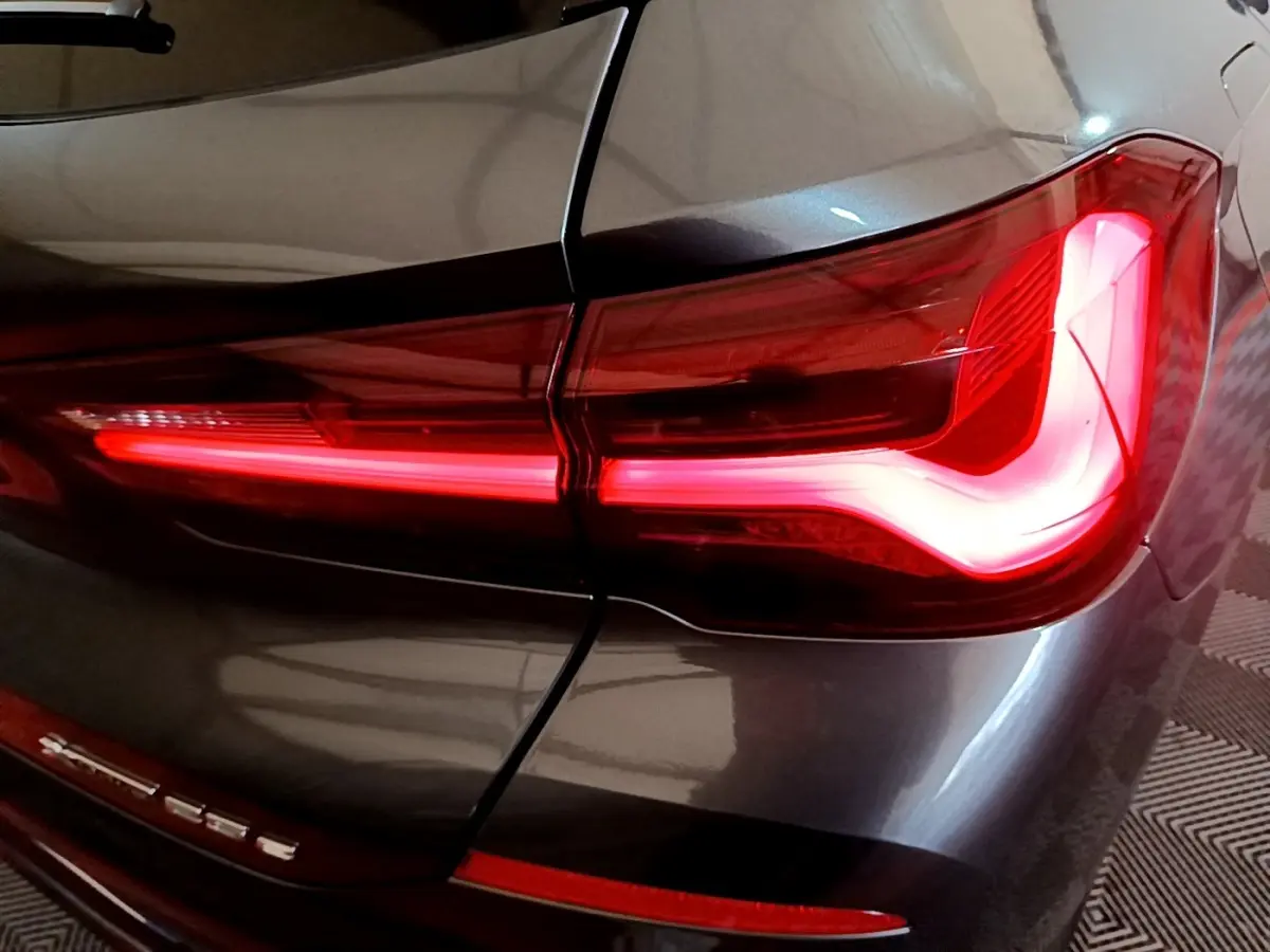 Gros plan sur le feu arrière droit rouge allumé du BMW X2 xDrive25e gris foncé, avec logo visible sur la malle arrière.