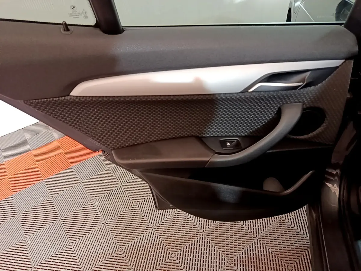 Détail de la porte arrière droite de BMW X2 hybride rechargeable, avec garniture noire texturée et poignée intégrée.